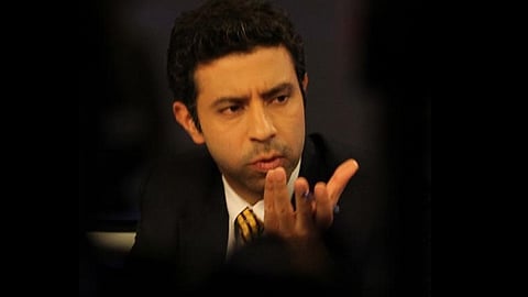 Rahul Shivshankar in a black suit and yellow tie. His face and half of his torso visible, rest of the image is blurred.