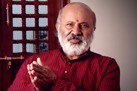 Actor Shivaram in a maroon kurta gesturing towards the camera