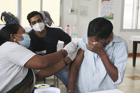 A beneficiary reacts while receiving a dose of COVID-19 vaccine