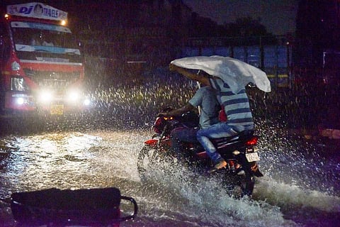 Two men riding on a motorcycle on a flooded street during rains