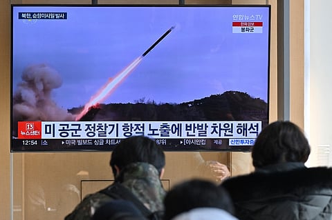 People watch a television screen showing a news broadcast with file footage of a North Korean missile test, at a railway station in Seoul on 24 January 2024. 