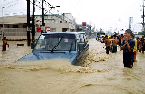 (FILES) A jeep plows through a submerged road while stranded passengers wade through floodwaters in Cebu on 7 November 2001. 