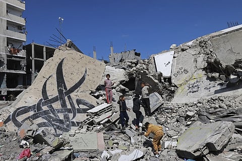 Children stand next to a fallen wall bearing a mural painting amid the rubble of a building destroyed in Israeli bombardment in Rafah in the southern Gaza Strip on February 22, 2024, amid continuing battles between Israel and the Palestinian militant group Hamas.
