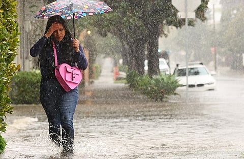 A person walks along a flooded street as a powerful long-duration atmospheric river storm, the second in less than a week, impacts California on 4 February 2024 in Santa Barbara, California. 
