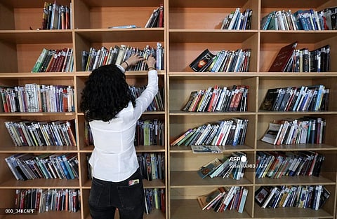 (FILES) A member of the Kurdistan Centre for Arts and Culture (KCAC), retrieves old books from the shelves before making digital copies, as part of an effort to digitize historic Kurdish volumes and manuscripts, in the northern Iraqi city of Dohuk on 13 February 2024. 
