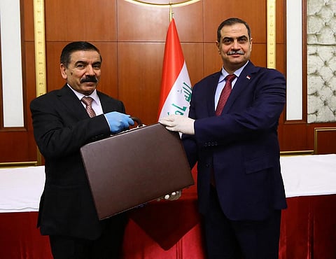 (FILES) This handout picture released and taken by the Iraqi Prime Minister's office shows outgoing defense minister Najah al-Shammari (R) handing over the post to his successor, Iraq's new defense minister Jumaa Inad, during a ceremony at Baghdad’s Republican Palace on 7 May 2020.