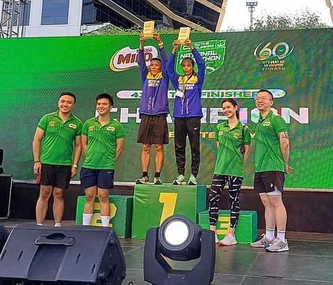 
Florendo Lapiz and Lizanne Abella (center) raise the plaques after winning the men’s and women’s full-marathon event of the 2024 National Milo Marathon Manila Leg yesterday at the Mall of Asia Concert Ground.