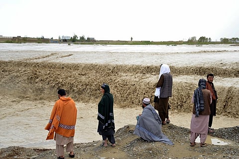 Afghan people wait to cross a flooded area in Spin Boldak district of Kandahar province on 13 April  2024, after a flash flood following a heavy rainfall.
