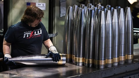 An employee handles 155 mm caliber shells