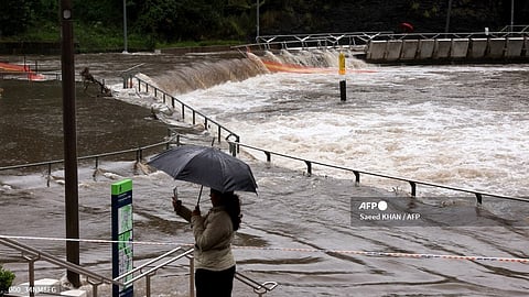 A woman takes pictures of the overflowing Parramatta River at the ferry wharf in Sydney on 5 April 2024, after heavy rain lashed eastern Australia, causing flash flooding and a string of emergency warnings up and down the Pacific coast.