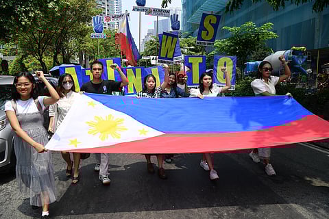 HAWAK ng mga nagpoprotesta ang watawat ng Pilipinas habang nagmamartsa patungo sa konsulada ng Tsina sa Maynila kahapon. Iginigiit sa mga karatula ng mga nagpoprotesta sa ang West Philippine Sea ay hindi sa Tsina.