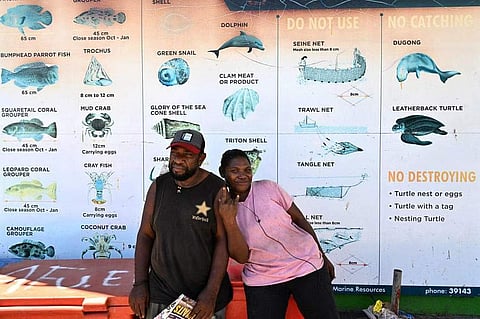Locals standing in front of a sign warning vendors against the live wildlife trade, in the capital city of the Solomon Islands, on April 21.

