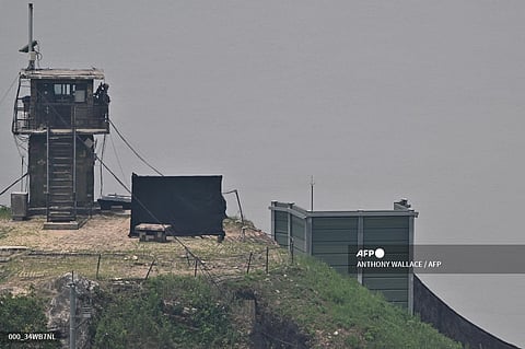 (FILE) A South Korean soldier stands guard near a military facility (R, green box) where loudspeakers dismantled in 2018 used to be, near the demilitarized zone separating the two Koreas in Paju on June 11, 2024. South Korean troops fired warning shots after North Korean soldiers briefly crossed the border this week, Seoul's military said on June 11, with tensions high over Pyongyang's trash-carrying balloons and the South's retaliatory loudspeaker campaign.