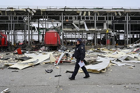 A Ukrainian policeman walks past a damaged mail depot following missile strikes in Korotych, Ukraine. 