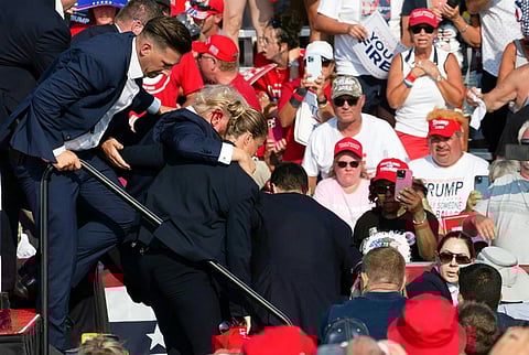 Republican candidate Donald Trump is seen with blood on his face surrounded by secret service agents. 