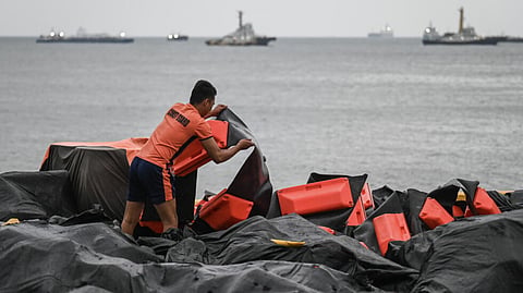 A coast guard staffer arranges an oil spill containment boom to be used in Manila Bay 