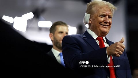A wounded Donald Trump with a bandaged right ear smiles and gives supporters a thumbs-up
