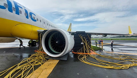 Workers from Cebu Pacific check on the aircraft that was lodged on a soft part along the runway at Ninoy Aquino International Airport Terminal 3 on Friday while being moved from a bay.

