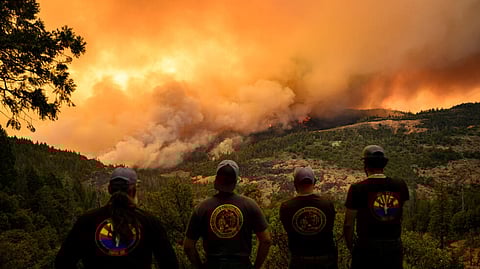 Firefighters watch as flames and smoke move through a valley in the Forest Ranch area of Butte County as the Park Fire continues to burn near Chico, California, on July 26, 2024 