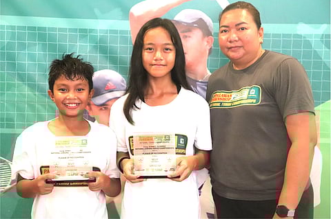 RAVEN Licayan and Ella Mhae Paglalunan hold their trophies as they pose with PPS-NTC tournament organizer Karen Arellano after winning the Rep. Edwin Olivarez National Tennis Championships at the Olivarez Sports Center in Parañaque City. 