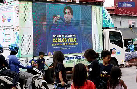 LOOK: Children played on NIA Road in Quezon City on 6 August 2024 as an MMDA LED truck celebrated Carlos Yulo, a two-time Olympic gold medalist. Sports advocates emphasized the importance of community parks and grassroots sports initiatives, inspired by Yulo's training at a Manila park where he prepared for and won two gold medals at the 2024 Paris Olympics.