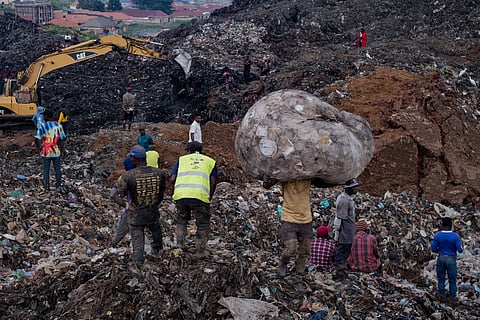 People look on as an excavator helps search for people trapped under debris after a landfill collapsed in Kampala on August 10, 2024. Nineteen people, including five children, are confirmed killed when mountains of garbage collapsed at a landfill in the Ugandan capital Kampala on August 10, the city authority said. 
