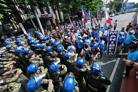 Personnel from the Manila Police District hold their ground as protesters comprising of members of transport groups Manibela and Piston try to march along Welcome Rotonda in Quezon City on Wednesday.