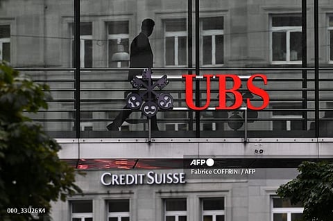 LOOK: An employee of UBS walks past a sign of Swiss giant banking above a sign of Credit Suisse on August 31, 2023 in Zurich, after the announcement by UBS of the first results since Credit Suisse merger. Banking giant UBS has decided that the Swiss unit of its recently-swallowed rival Credit Suisse will be "fully integrated" into its operations, and thus disappear, without spelling out the implications for job cuts. | 📷 Fabrice COFFRINI / AFP