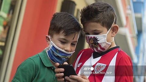 Two kids look at a smartphone