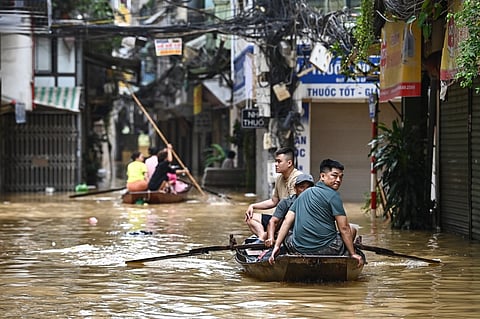 People wade through flood waters on a boat in Hanoi on September 12, 2024, as heavy rains in the aftermath of Typhoon Yagi brought flooding to northern Vietnam. The number of people killed after Typhoon Yagi swept through northern Vietnam bringing flash floods and landslides has risen to 197, the government said on September 12.
