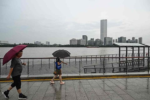 People walking on a pedestrian walkway along the Huangpu river in Shanghai.