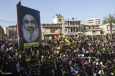 Supporters of Lebanon's Iran-backed Shiite group Hezbollah, wave the group's, Lebanese, and Iranian flags as they rally to attend a speech by Hezbollah leader Hassan Nasrallah (billboard portrait), broadcast on a giant screen, in the southern city of Nabatiyeh, on 9 May, 2022. Israel's military announced on September 28, 2024 that Nasrallah was killed in an Israeli strike on Beirut the previous night, but there was no confirmation from the Lebanese armed group.
