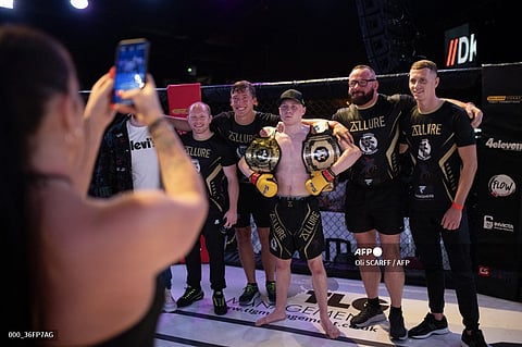 Mixed martial arts fighter Joe Frodsham (C) poses with his coaches and belts following his cage fight victory against Garon Shemar for the vacant 'GTFP 61.2kg Championship' at an evening of MMA combat hosted by 'Golden Ticket Fight Promotions' in Wolverhampton, central England, on September 7, 2024. Mixed Martial Arts fighting is a full-contact combat sport based on techniques of striking, throwing, kicking, and grappling with an opponent, often incorporating techniques from various combat sports including: boxing, wrestling, kickboxing and martial arts. Cage fighting events attract an international roster of fighters in both the amateur and professional categories.
Oli SCARFF / AFP