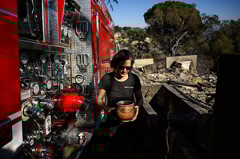 Robin Wallace carries a bowl of fish she saved from the pond of her family’s home on West Highland Drive after it was engulfed in flame and destroyed by the wind driven Mountain Fire wildfire on 8 November, 2024 in Camarillo, California. More than 130 homes are now known to have been destroyed by a raging wildfire burning outside Los Angeles, as a break in the weather on November 8 gave firefighters a chance to tame the blaze. Hurricane-strength winds that battered the area this week fuelled an explosion in the Mountain Fire near Camarillo, which grew rapidly to over 20,000 acres (8,000 hectares).
