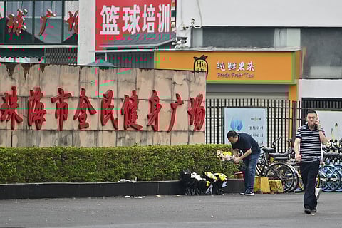 Workers remove flowers from a makeshift memorial outside the Zhuhai Sports Center in Zhuhai in south China’s Guangdong province on 13 November 2024, two days after 35 people were killed when a man drove a car into a crowd in one of the country’s deadliest mass-casualty events in years. 