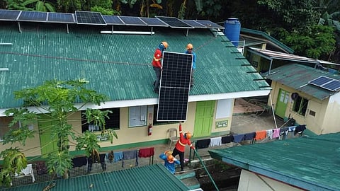 Workers install solar panels on the roof of the Iram II Elementary School in Olongapo, Zambales.