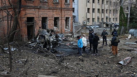 Ukrainian law enforcement officers and local residents stand among debris in the courtyard of a damaged residential building following a missile attack in Kharkiv 