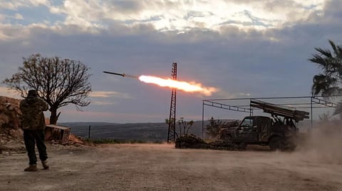 An anti-government fighter covers his ears as a multi-barrel rocket launcher fires against government forces, in the northern outskirts of Syria's city of Hama 