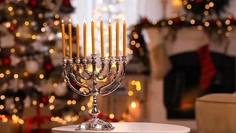 A menorah glows brightly beside a festive Christmas tree, symbolizing the unique overlap of Hanukkah and Christmas celebrations this year.