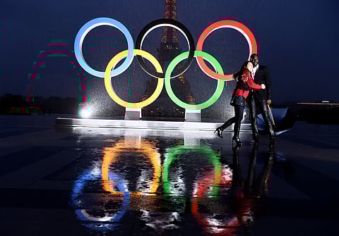 A couple poses in the rain ahead of the opening ceremony of the Paris Olympics. 