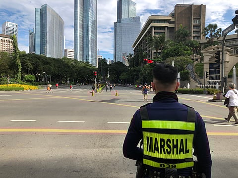 At Ayala and Makati Avenue, a marshal watches as cyclists, skaters and joggers bring the car-free streets to life.