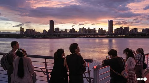 People take pictures of Taipei's skyline along the bank of Tamsui River during sunset from the Dadaocheng Wharf popular tourist spot in Taipei on Sep 16, 2024. 