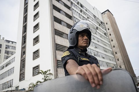 A police officer looks on as he stands guard at the National Prosecutor’s headquarters building in Lima before the arrival of Peruvian President Dina Boluarte in Lima on 13 January 2025. The president of Peru, Dina Boluarte, appears this Monday before prosecutors investigating her for the alleged crime of abandonment of office and omission of functional acts, due to the fact that she did not inform the ministerial cabinet and Congress that she would undergo a nose job in July 2023.