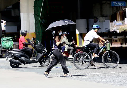 A female pedestrian uses her umbrella to protect herself from intense heat along EDSA in Quezon City last November 2024. PAGASA said that the northeast monsoon is expected to surge until midweek of March.