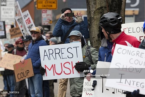People participate in a "TeslaTakedown" protest against Elon Musk outside of a Tesla showroom in Seattle, Washington, on February 15, 2025. Musk leads the efforts under the newly created Department of Government Efficiency (DOGE), and was speaking at the White House with Trump, who has in recent weeks issued a flurry of orders aimed at slashing federal spending. 