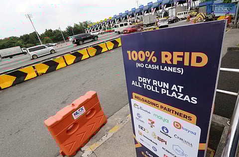 Security guard arranges an RFID toll sign while Motorists pass through at the Balintawak RFID toll gate on the North Luzon Expressway (NLEX) in Caloocan City on Tuesday, 18 February 2025. Starting 15 March, cashless or contactless toll collection will be enforced on major tollways, including NLEX, as announced by the Toll Regulatory Board (TRB) to improve traffic flow and efficiency. Vehicles with insufficient funds will incur fines of P1,000 for the first offense, P2,000 for the second offense, and P5,000 for each subsequent violation. While vehicles with RFID can still enter NLEX, they will be redirected to the nearest customer service center for installation. 