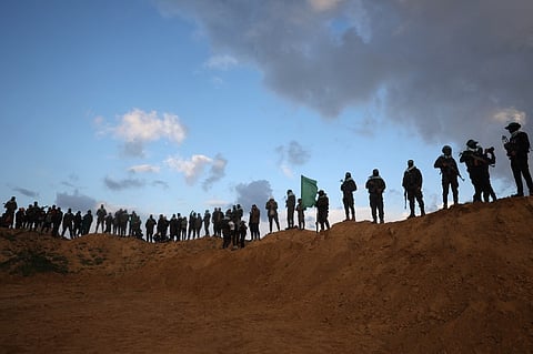 Palestinian militant group Hamas fighters stand at attention ahead of the handing over of the bodies of four Israeli hostages in Khan Yunis in southern Gaza on 20 February 2025. Hamas is due to hand over the bodies of four hostages on February 20, including those of the Bibas family, who have become symbols of the hostage crisis that has gripped Israel since the Gaza war broke out. The transfer of the bodies is the first such handover of remains by Hamas since its 7 October 2023 attack on Israel triggered the war.