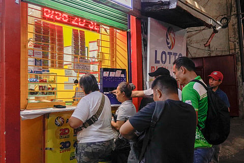 PEOPLE fall in line at a lottery stand in Cubao, Quezon City in hopes of winning a big prize.