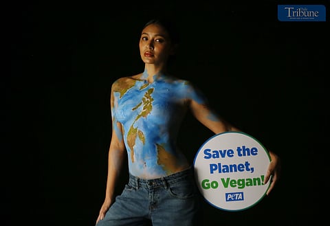 Actress and singer Nadine Lustre, wearing only body paint, holds a "Save the Planet, Go Vegan" sign while posing as Mother Earth during a photo shoot in Pasig City on 17 March  2025. Lustre promotes the vegan lifestyle as part of a campaign by People for the Ethical Treatment of Animals (PETA).