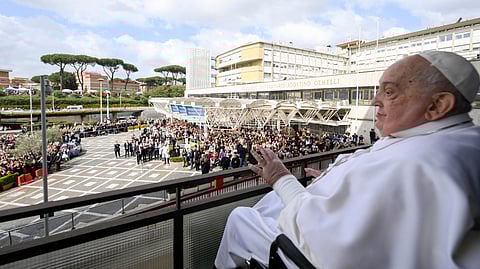 This photo taken and handout on 23 March 2025 by The Vatican Media shows Pope Francis waving to the crowd from a window of the Gemelli hospital in Rome before being discharged following a five weeks hospitalization for pneumonia.